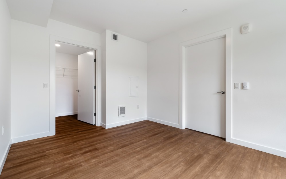 a bedroom with wood floors and white walls