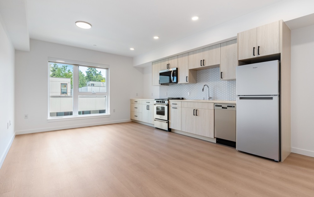 an empty kitchen and living room with wood floors and a window